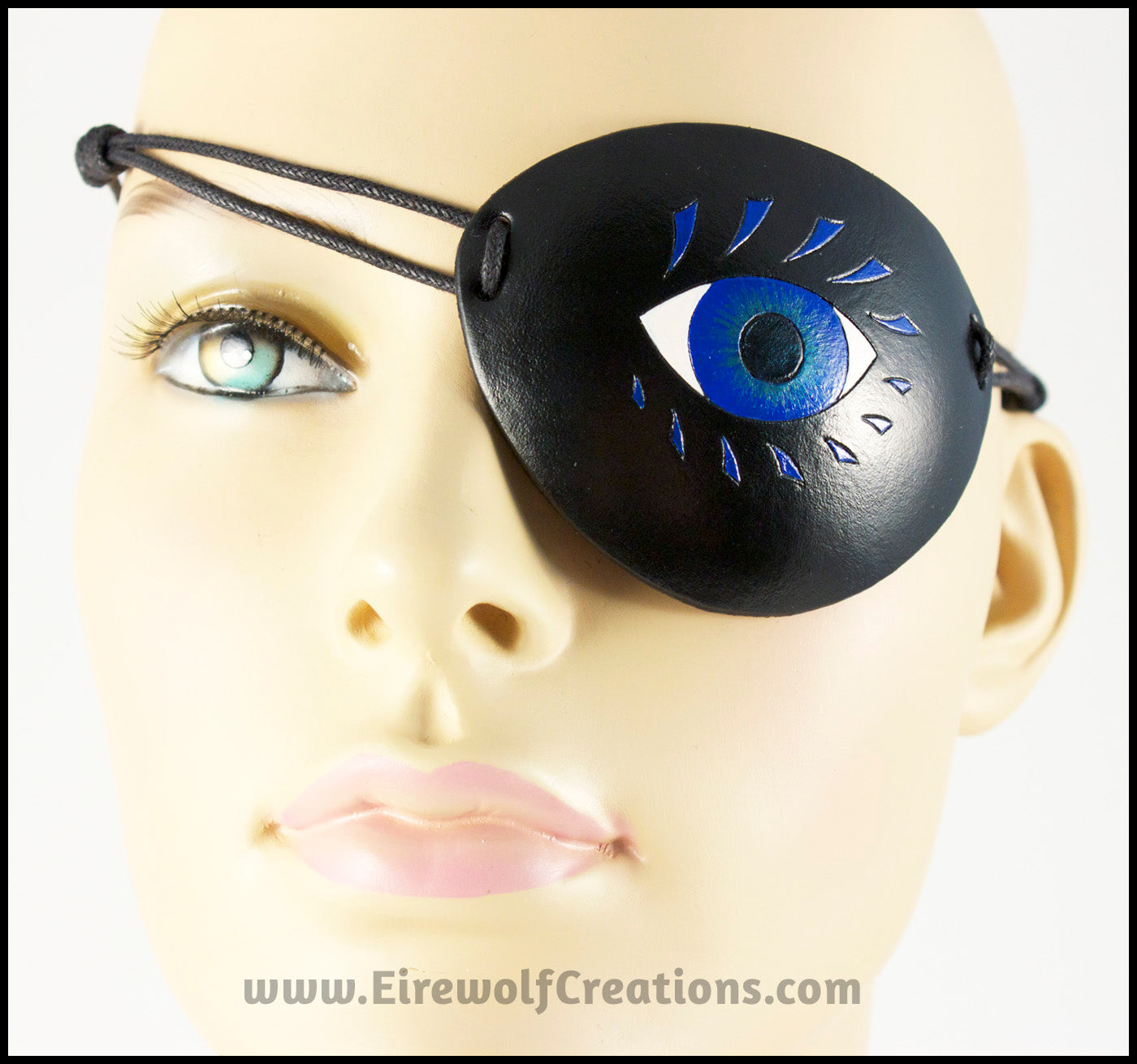 A bold graphic stylized blue eye with blue eyelashes carved and painted onto a handmade black leather eye patch, for a masquerade costume or pirate cosplay. By Erin Metcalf of Eirewolf Creations.