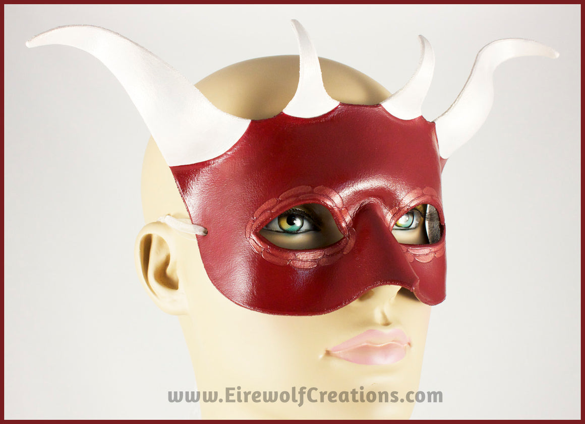 A handmade leather Red Dragon mask with four white horns and scale details around the eyes. By Erin Metcalf of Eirewolf Creations.