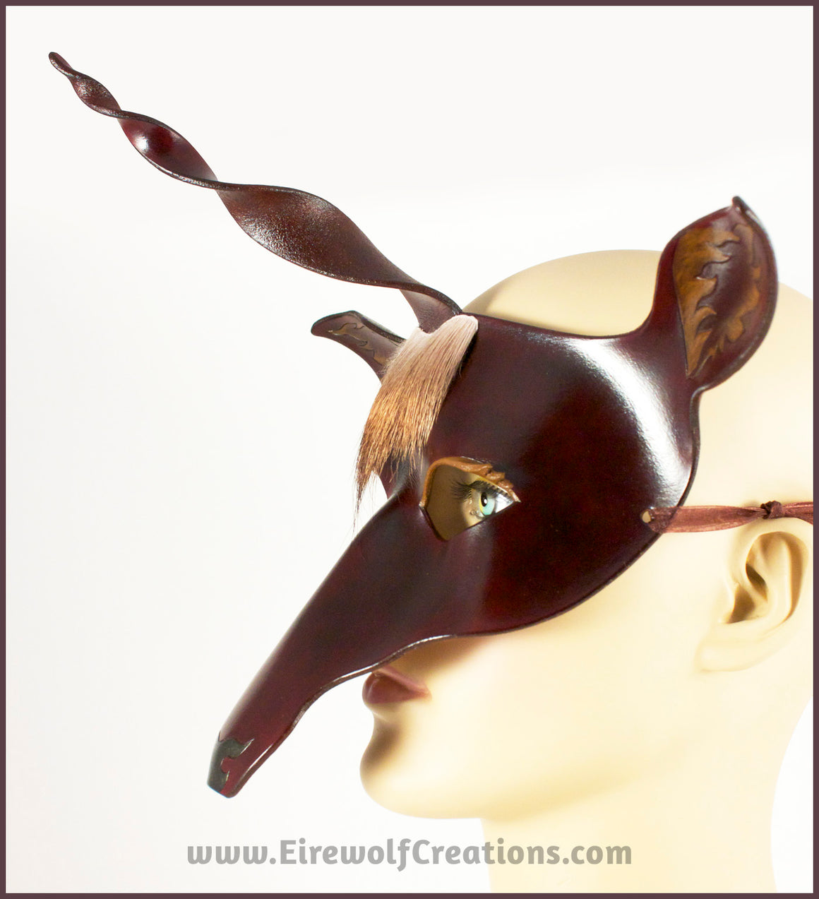 The Dark Forest Unicorn is a dark brown handmade leather masquerade mask of a deerlike unicorn with real deer hair as a forelock. By Erin Metcalf of Eirewolf Creations.