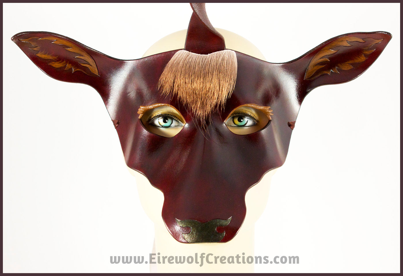 The Dark Forest Unicorn is a dark brown handmade leather masquerade mask of a deerlike unicorn with real deer hair as a forelock. By Erin Metcalf of Eirewolf Creations.