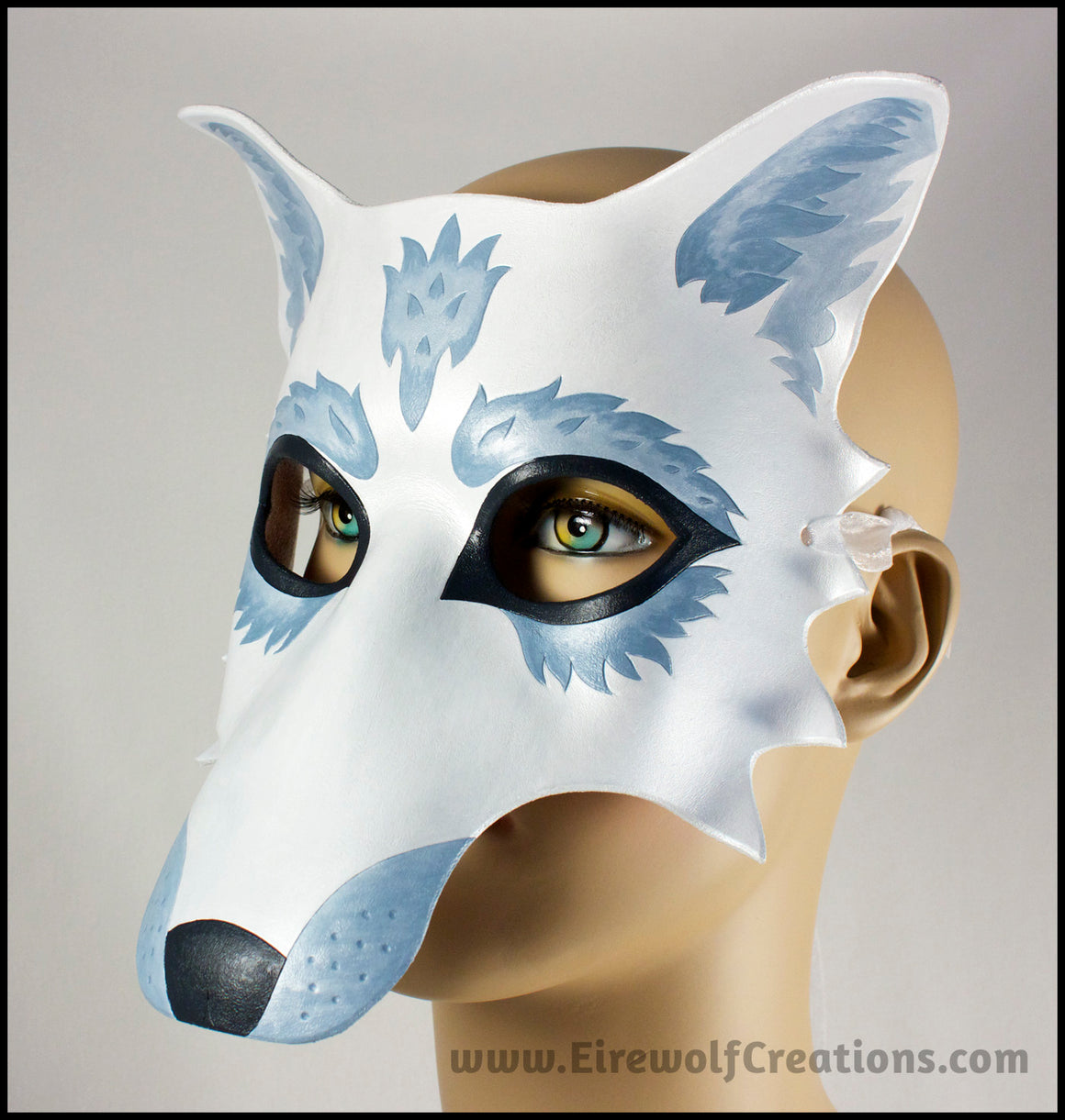 A handmade leather masquerade costume mask of a winter white wolf with silver fur details. By Erin Metcalf of Eirewolf Creations.