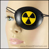A handmade leather eye patch with a carved and painted radiation hazard symbol in black and yellow, for a masquerade costume or pirate cosplay. By Erin Metcalf of Eirewolf Creations.