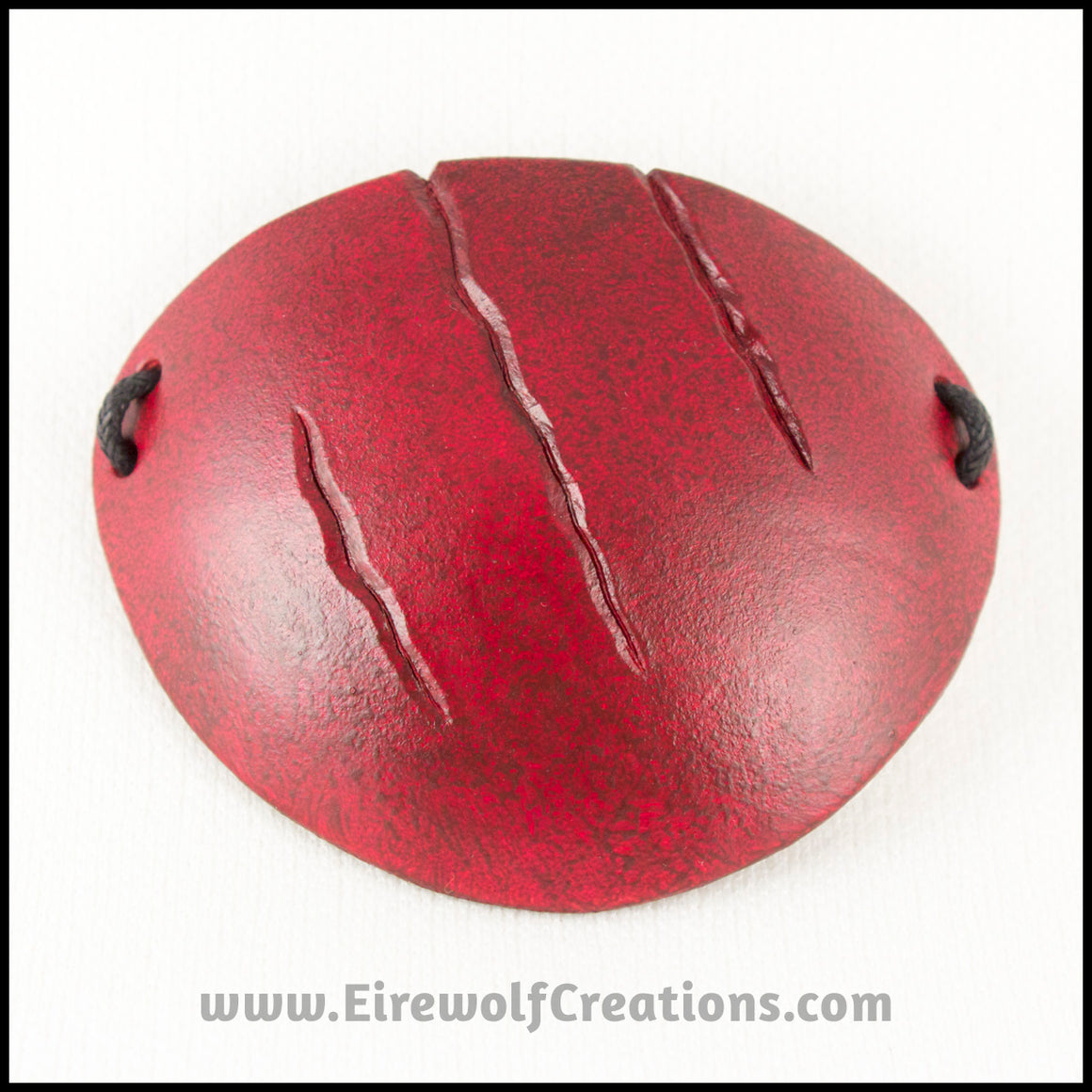 A handmade leather eye patch with three jagged scars carved diagonally, dyed and painted a mottled red reminiscent of blood, for a masquerade costume or assassin or pirate cosplay. By Erin Metcalf of Eirewolf Creations.