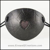 A handmade leather eye patch with a heart cut out, subtly iridescent black, backed with transparent black fabric to allow some visibility, for a masquerade costume or pirate cosplay. By Erin Metcalf of Eirewolf Creations.