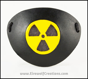 A handmade leather masquerade costume eye patch with a radiation hazard symbol cut out of the leather, painted black and bright yellow and backed with transparent black fabric to allow some visibility. By Erin Metcalf of Eirewolf Creations.