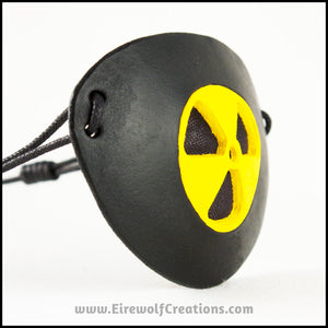 A handmade leather masquerade costume eye patch with a radiation hazard symbol cut out of the leather, painted black and bright yellow and backed with transparent black fabric to allow some visibility. By Erin Metcalf of Eirewolf Creations.