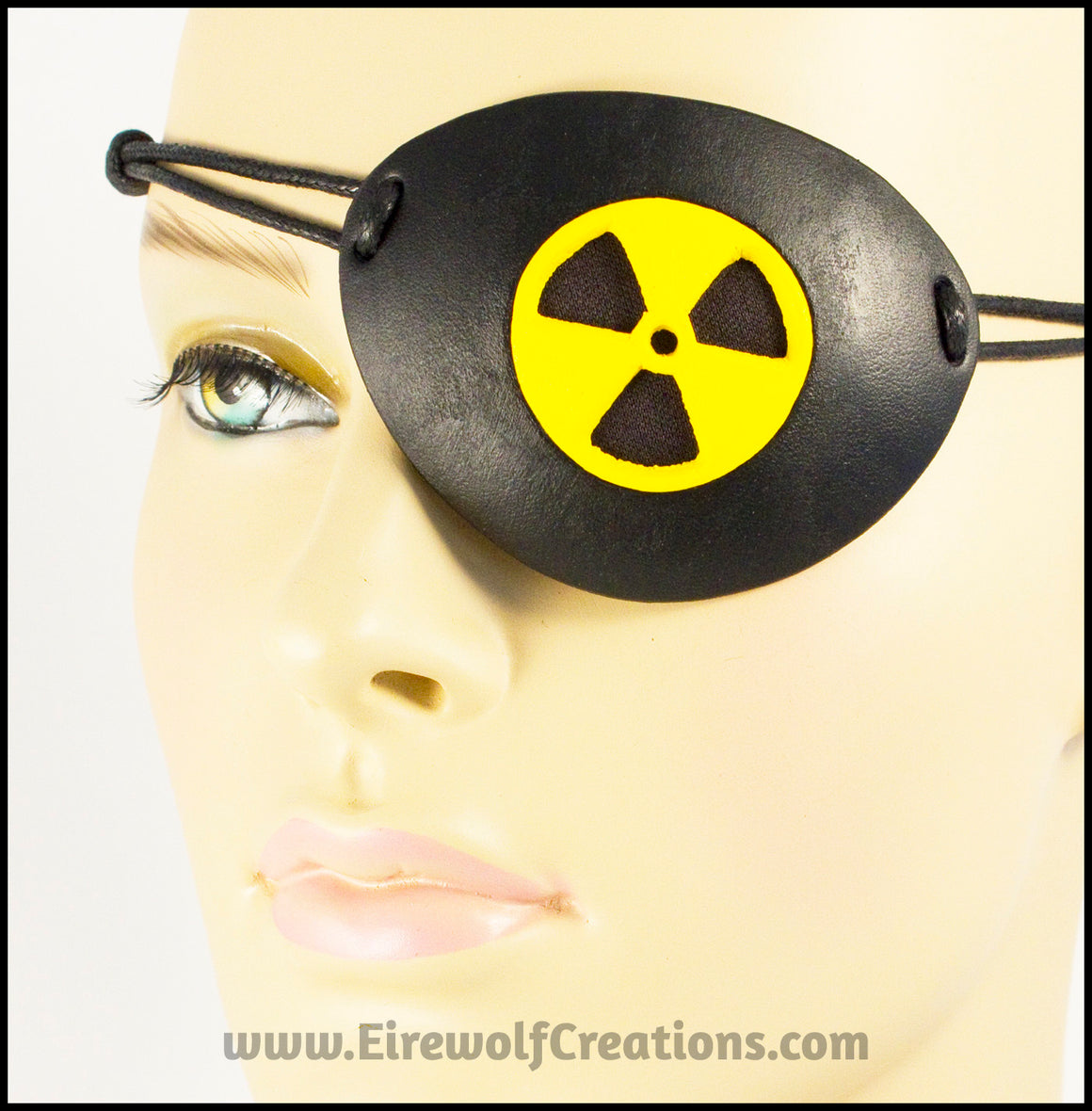 A handmade leather masquerade costume eye patch with a radiation hazard symbol cut out of the leather, painted black and bright yellow and backed with transparent black fabric to allow some visibility. By Erin Metcalf of Eirewolf Creations.