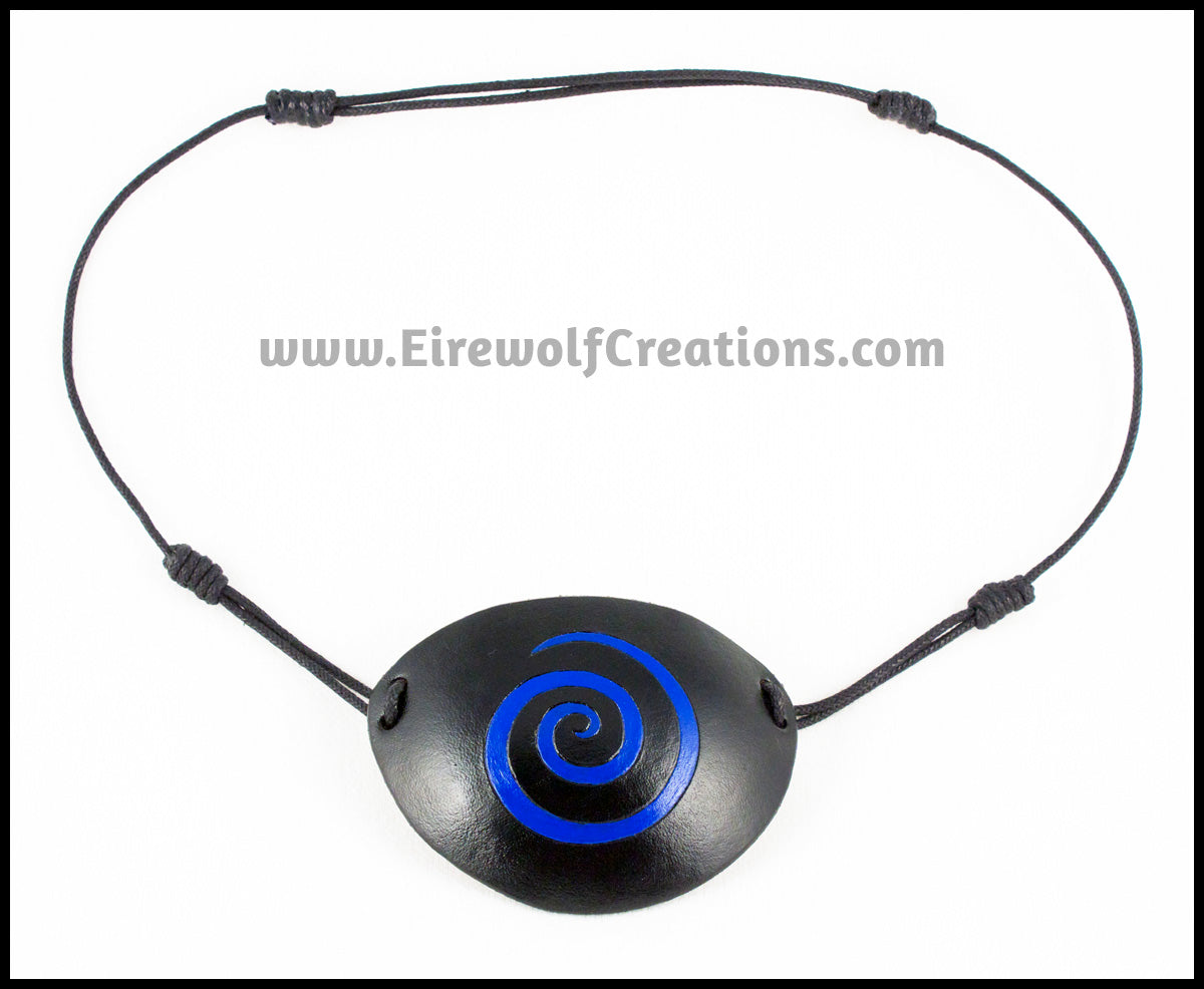 A handmade black leather eye patch with a carved and painted cobalt blue spiral, for a masquerade costume or pirate cosplay. By Erin Metcalf of Eirewolf Creations.