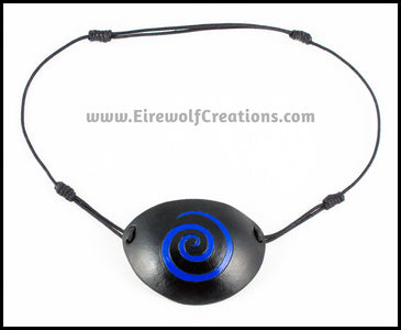 A handmade black leather eye patch with a carved and painted cobalt blue spiral, for a masquerade costume or pirate cosplay. By Erin Metcalf of Eirewolf Creations.