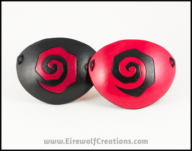 Handmade leather eye patches with a chunky Burtonesque spiral carved and painted red and black, for a masquerade costume or pirate cosplay. By Erin Metcalf of Eirewolf Creations.