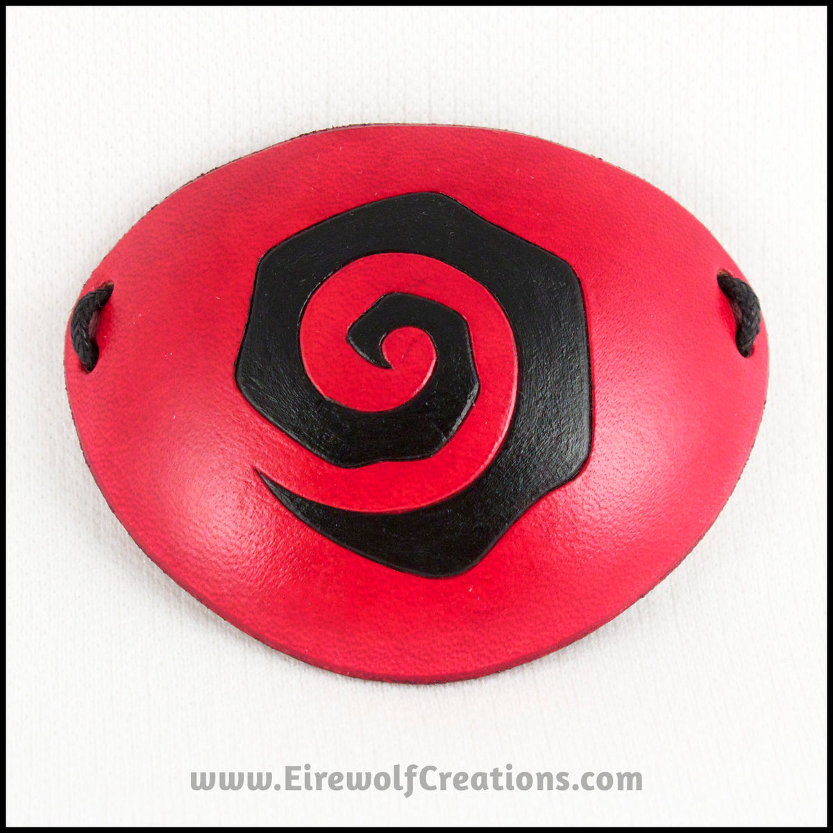 Handmade leather eye patches with a chunky Burtonesque spiral carved and painted red and black, for a masquerade costume or pirate cosplay. By Erin Metcalf of Eirewolf Creations.