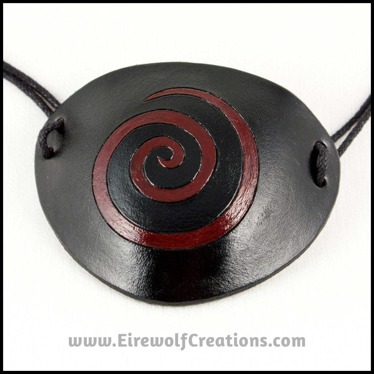 A thin spiral carved and painted dark red onto a handmade black leather eye patch, for a masquerade costume or pirate cosplay. By Erin Metcalf of Eirewolf Creations.