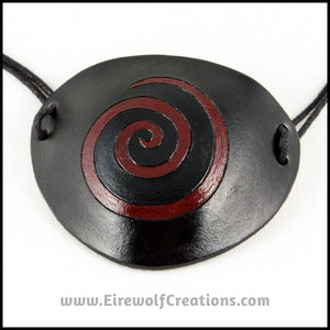 A thin spiral carved and painted dark red onto a handmade black leather eye patch, for a masquerade costume or pirate cosplay. By Erin Metcalf of Eirewolf Creations.