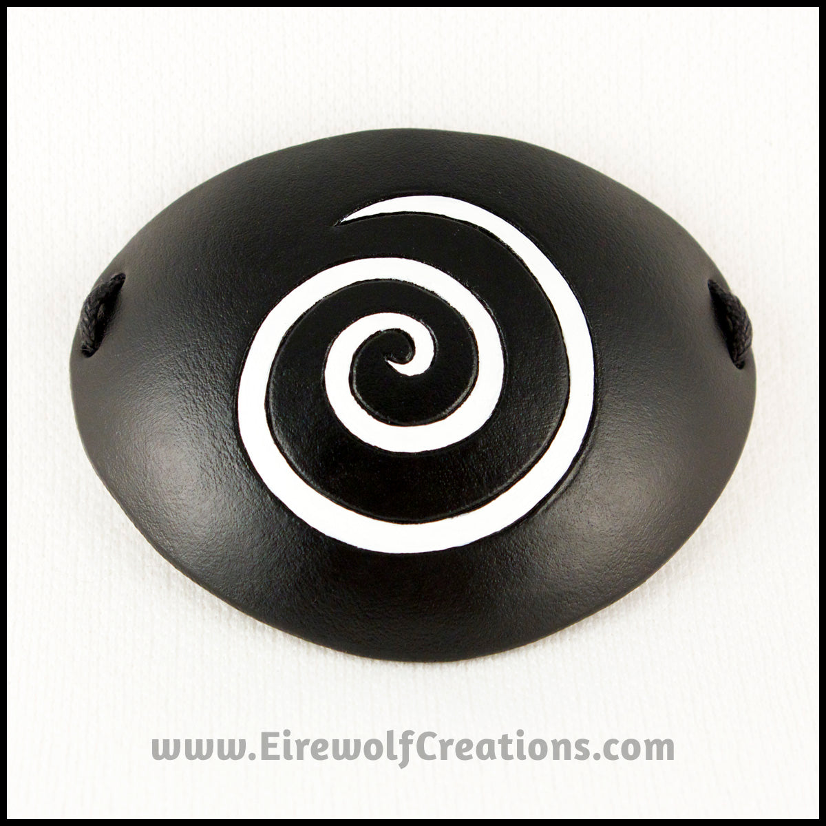 A thin spiral carved and painted white onto a handmade black leather eye patch, for a masquerade costume or pirate cosplay. By Erin Metcalf of Eirewolf Creations.