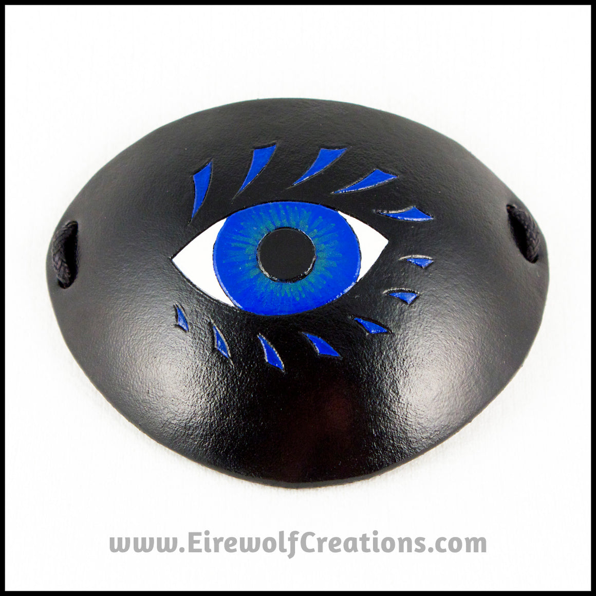 A bold graphic stylized blue eye with blue eyelashes carved and painted onto a handmade black leather eye patch, for a masquerade costume or pirate cosplay. By Erin Metcalf of Eirewolf Creations.