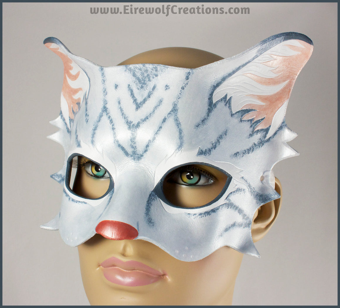 A handmade leather silver-gray tabby cat mask for a masquerade costume, with handpainted stripes, a dark pink nose and light pink inner ears. By Erin Metcalf of Eirewolf Creations.
