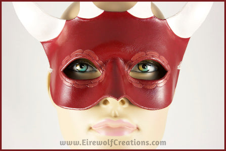 Closeup of a handmade leather Red Dragon mask with four white horns and scale details around the eyes. By Erin Metcalf of Eirewolf Creations.