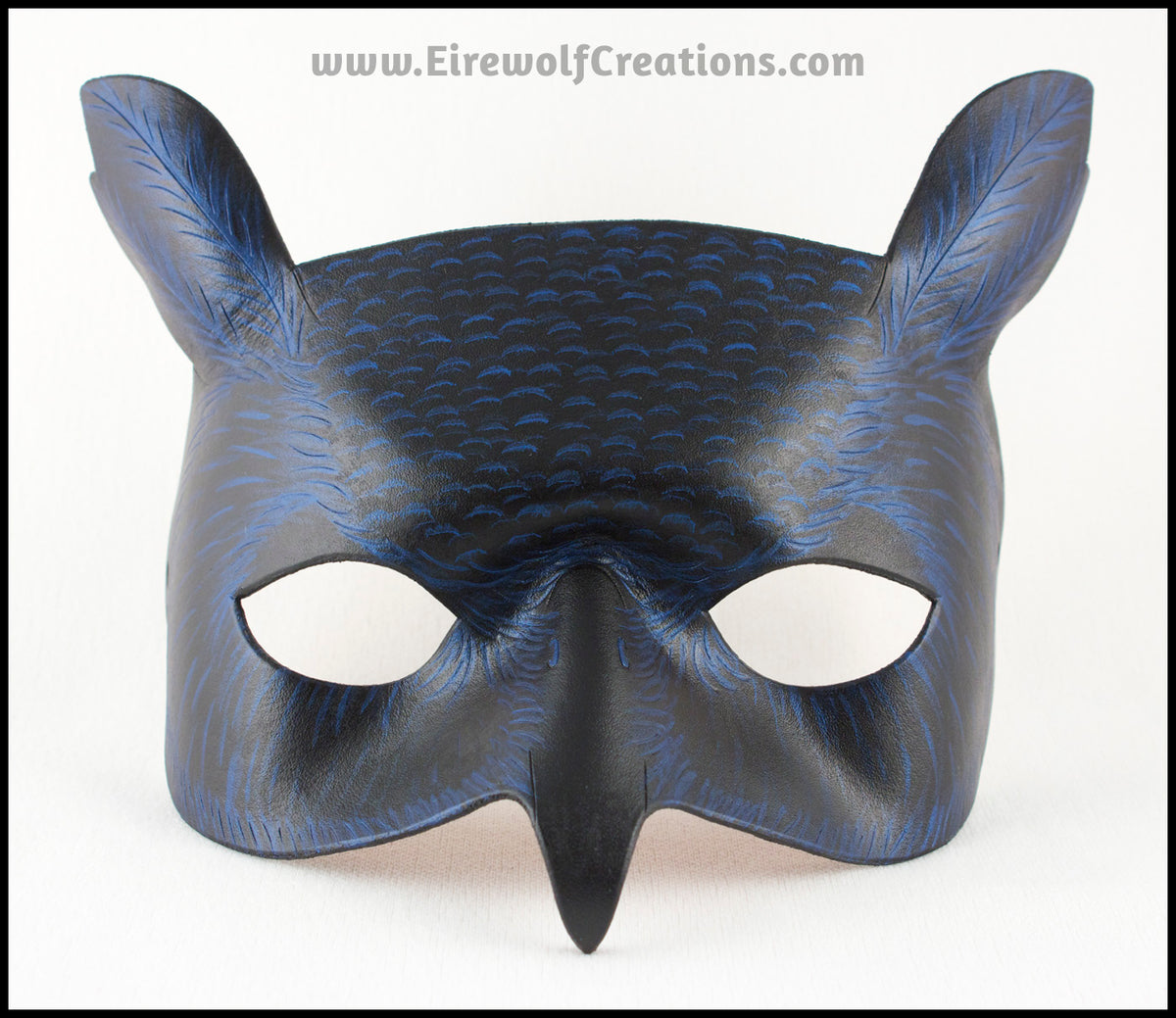 A Great Horned Owl handmade leather masquerade costume mask, alternate color dyed black and carved and painted with iridescent blue feather details. By Erin Metcalf of Eirewolf Creations.
