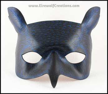 A Great Horned Owl handmade leather masquerade costume mask, alternate color dyed black and carved and painted with iridescent blue feather details. By Erin Metcalf of Eirewolf Creations.