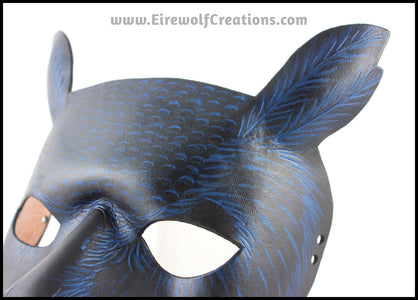 A Great Horned Owl handmade leather masquerade costume mask, alternate color dyed black and carved and painted with iridescent blue feather details. By Erin Metcalf of Eirewolf Creations.