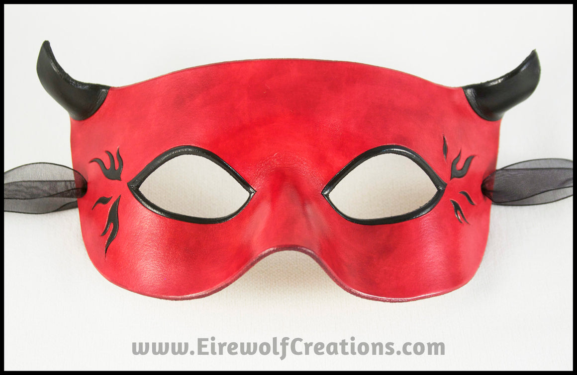 A handmade leather Horned Red Devil mask for a masquerade costume, with small black horns and black hot rod style flames. By Erin Metcalf of Eirewolf Creations.