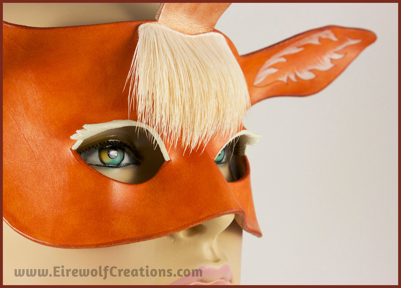 Closeup of a handmade leather palomino unicorn mask for a masquerade costume, with a twisting horn and cream-colored forelock made of real deer hair. By Erin Metcalf of Eirewolf Creations.